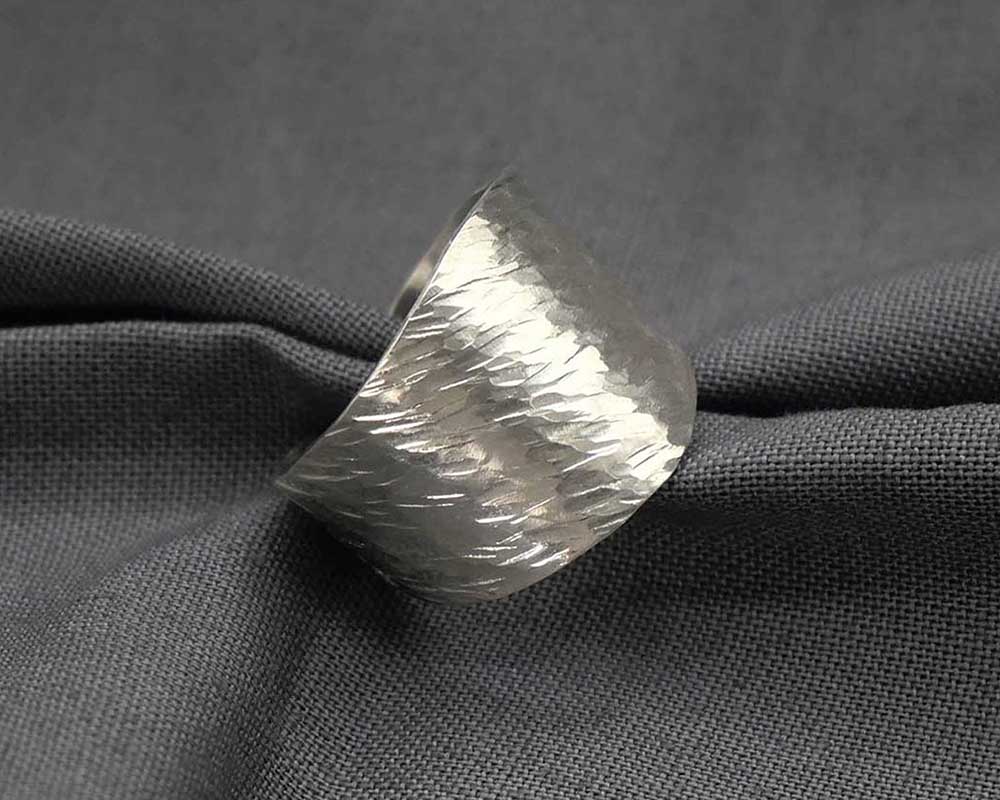 Bague réglable texturée en argent sur un tissu. 